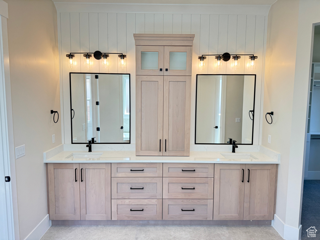 Full bath with baseboards and double vanity