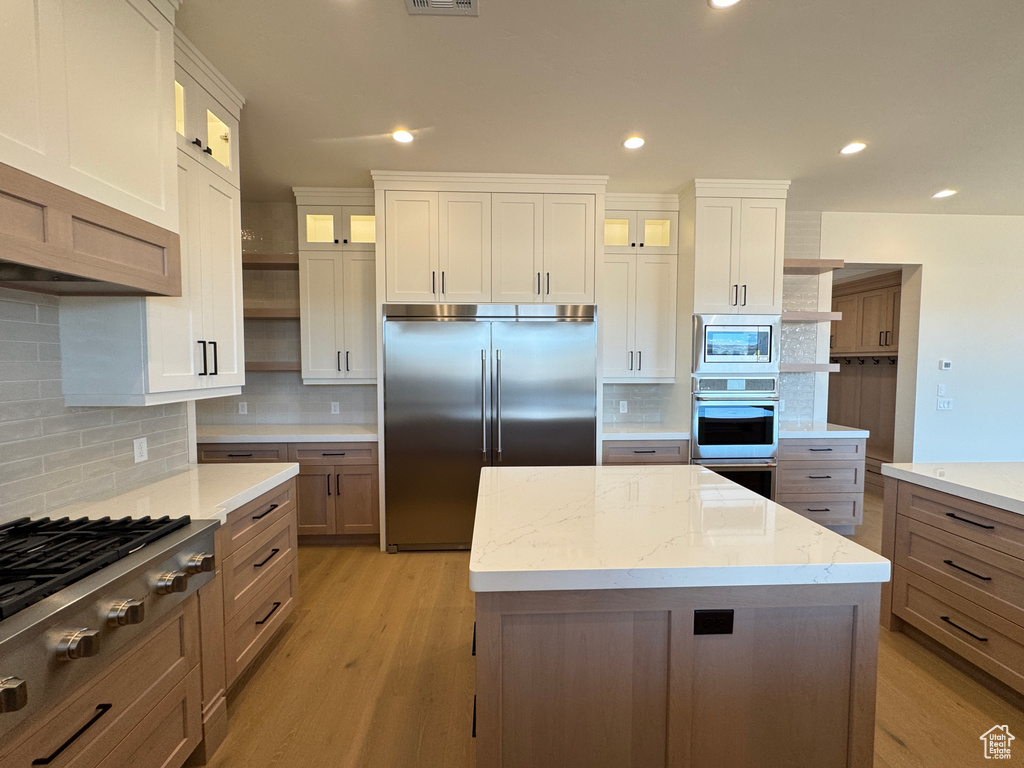 Kitchen with built in appliances, open shelves, tasteful backsplash, light wood-type flooring, and recessed lighting