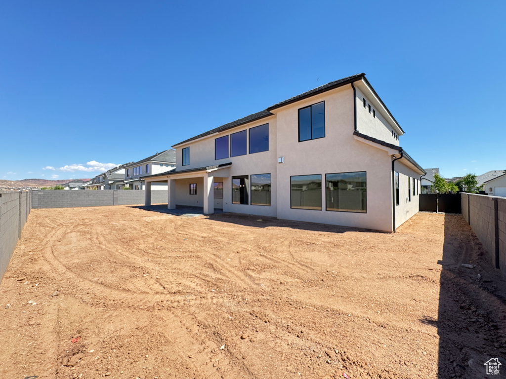 Back of property with a fenced backyard and stucco siding