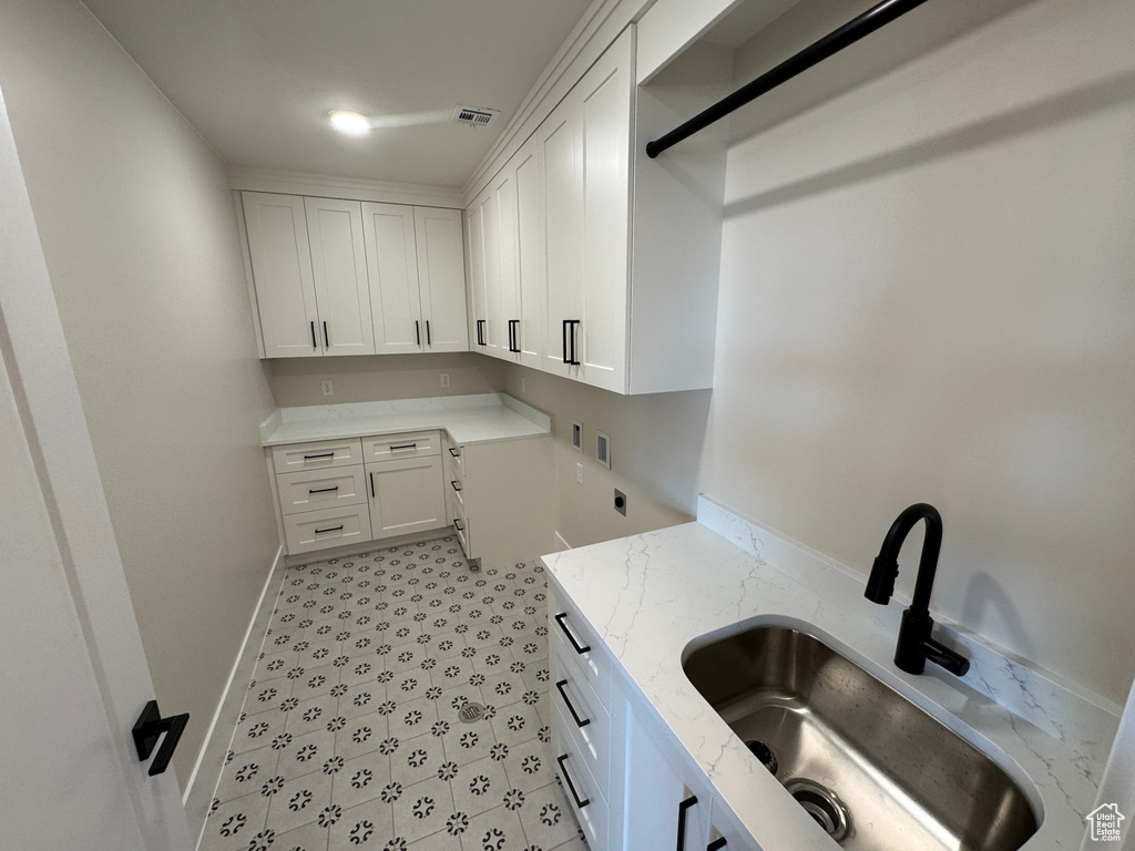 Laundry room featuring cabinet space, light floors, and baseboards