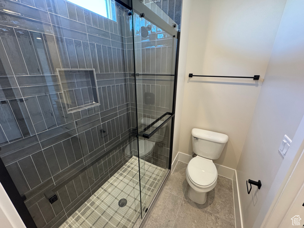 Bathroom with toilet, a stall shower, and baseboards