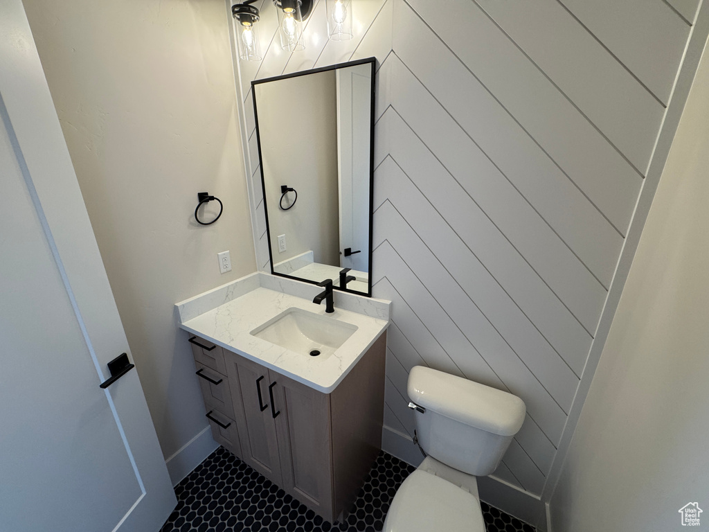 Half bathroom featuring toilet, vanity, tile patterned flooring, and baseboards