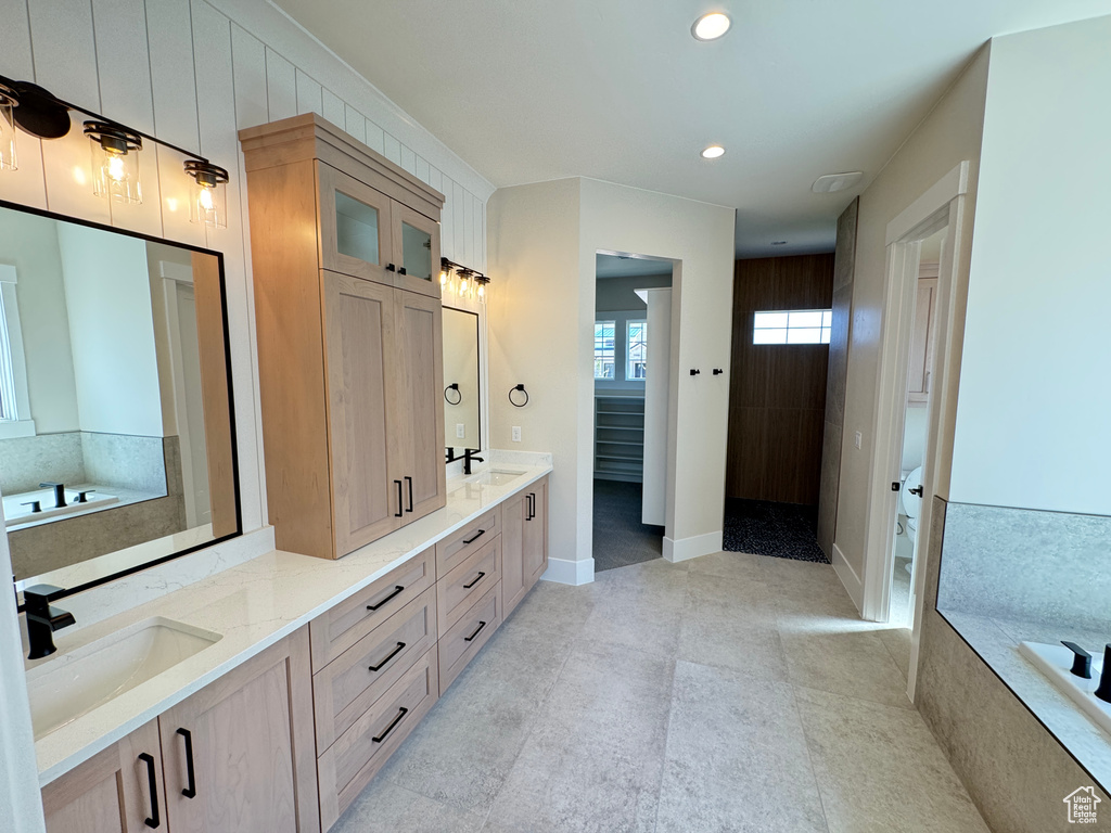Full bathroom with double vanity, a tub, tile patterned flooring, recessed lighting, and baseboards