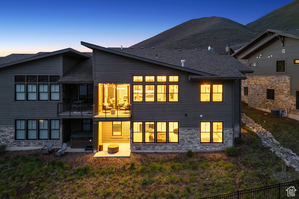 Rear view of property featuring stone siding, central air condition unit, and a mountain view