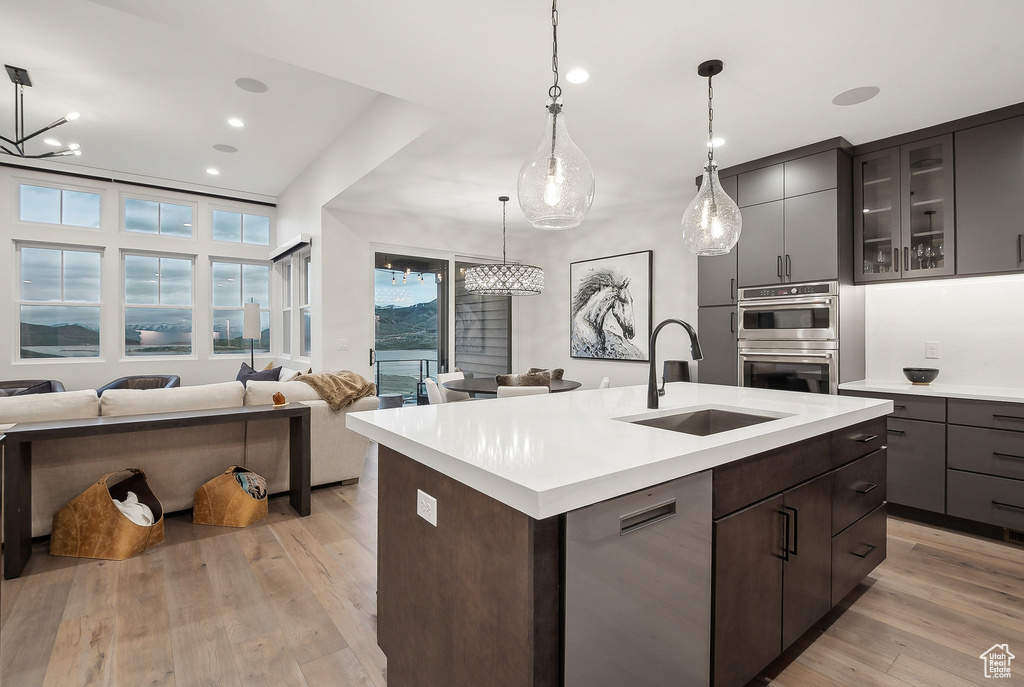 Kitchen featuring a sink, stainless steel appliances, light countertops, open floor plan, and recessed lighting