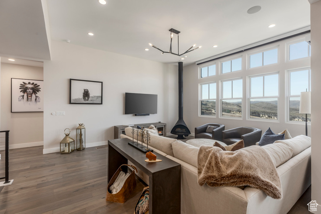 Living room featuring dark wood-style floors, baseboards, recessed lighting, a wood stove, and a chandelier