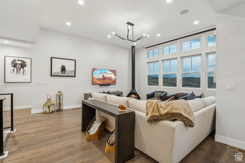Living room featuring baseboards, recessed lighting, wood finished floors, a chandelier, and a wood stove