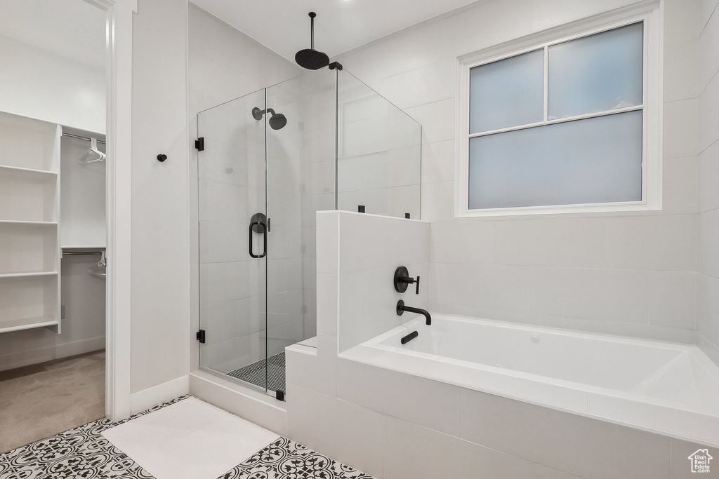 Full bathroom featuring a stall shower, a walk in closet, and a bath