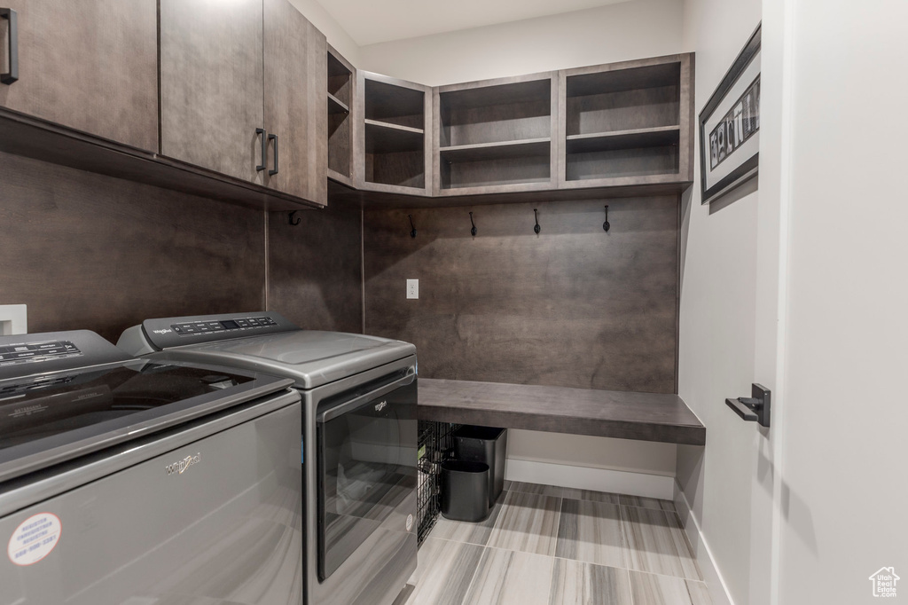 Laundry area featuring washing machine and clothes dryer, baseboards, and cabinet space