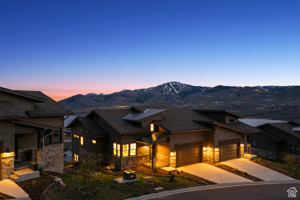 Contemporary home featuring stone siding, a garage, driveway, and a mountain view
