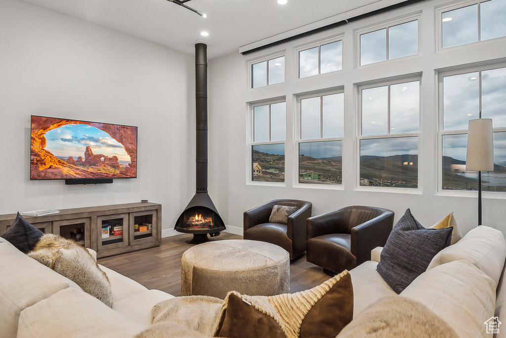Living room with wood finished floors, recessed lighting, a wood stove, and baseboards