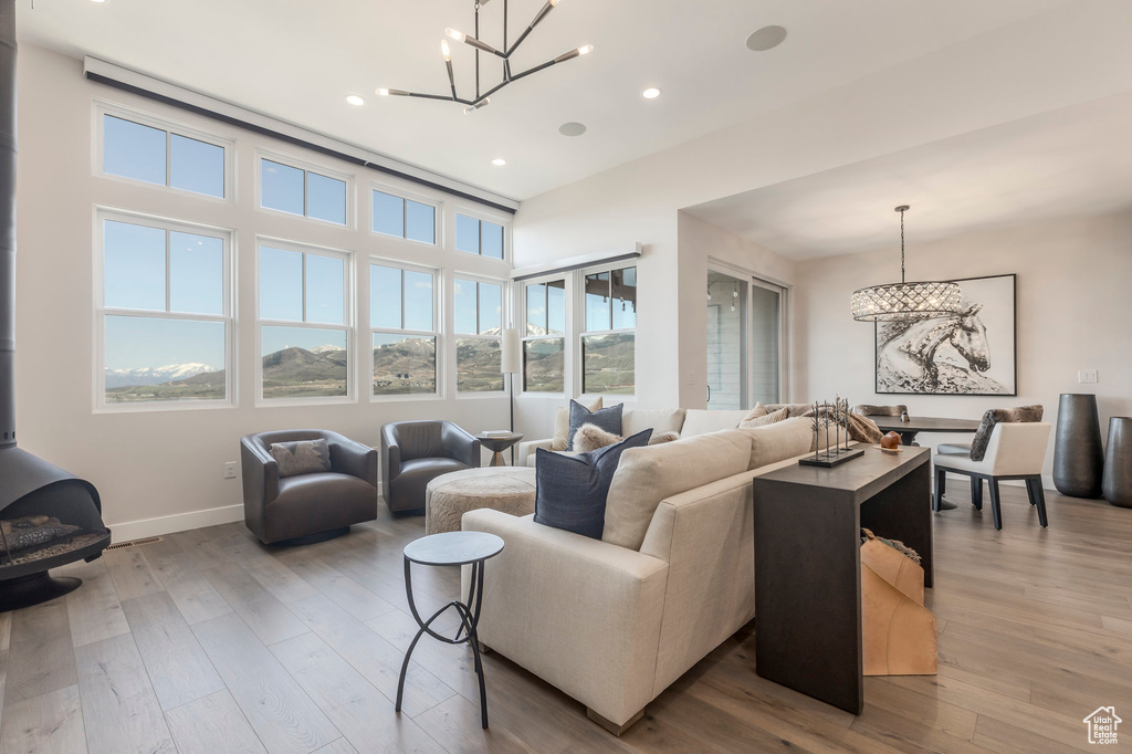 Living room with a chandelier, a wood stove, wood finished floors, recessed lighting, and baseboards