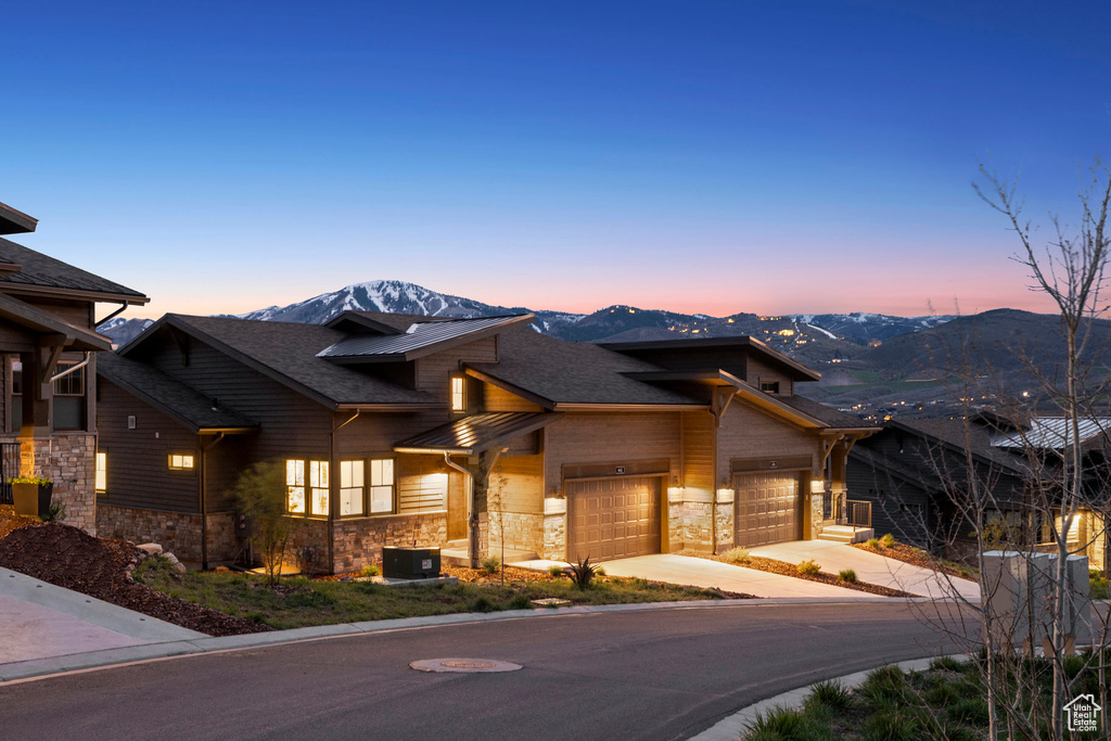 View of front of house featuring stone siding, concrete driveway, a garage, and a mountain view