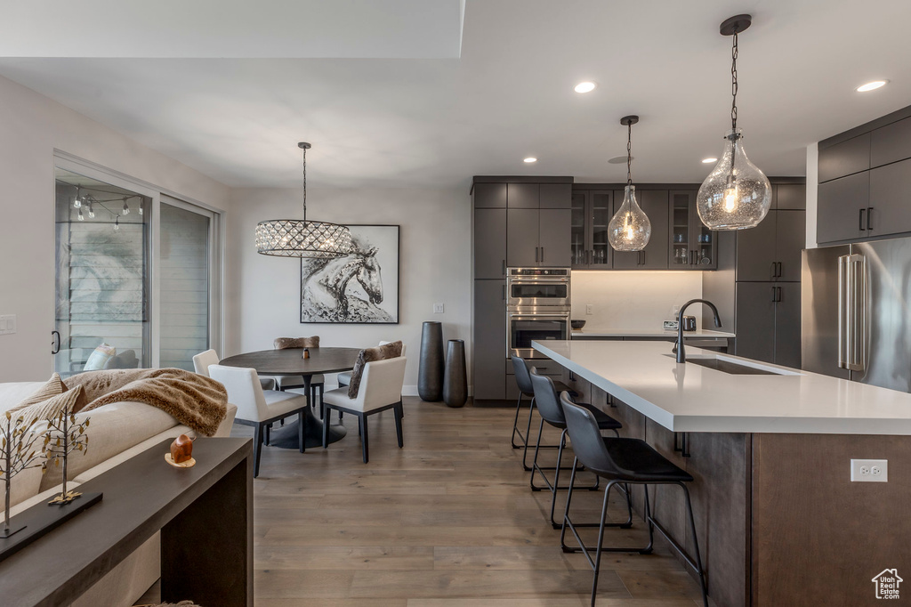 Kitchen with a sink, stainless steel appliances, gray cabinetry, a breakfast bar, and recessed lighting