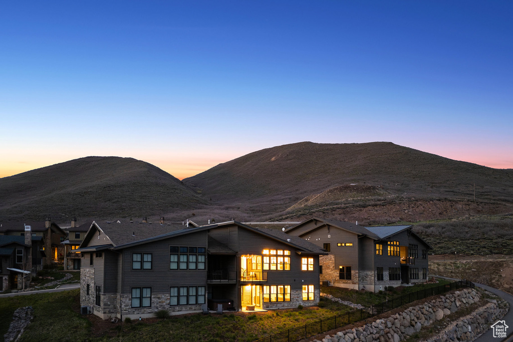 Back of house featuring a balcony, stone siding, and a mountain view
