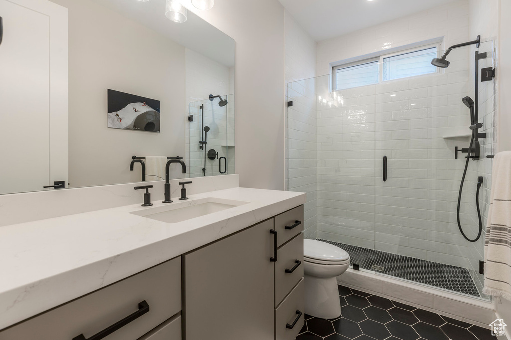 Bathroom with a shower stall, vanity, tile patterned floors, and toilet
