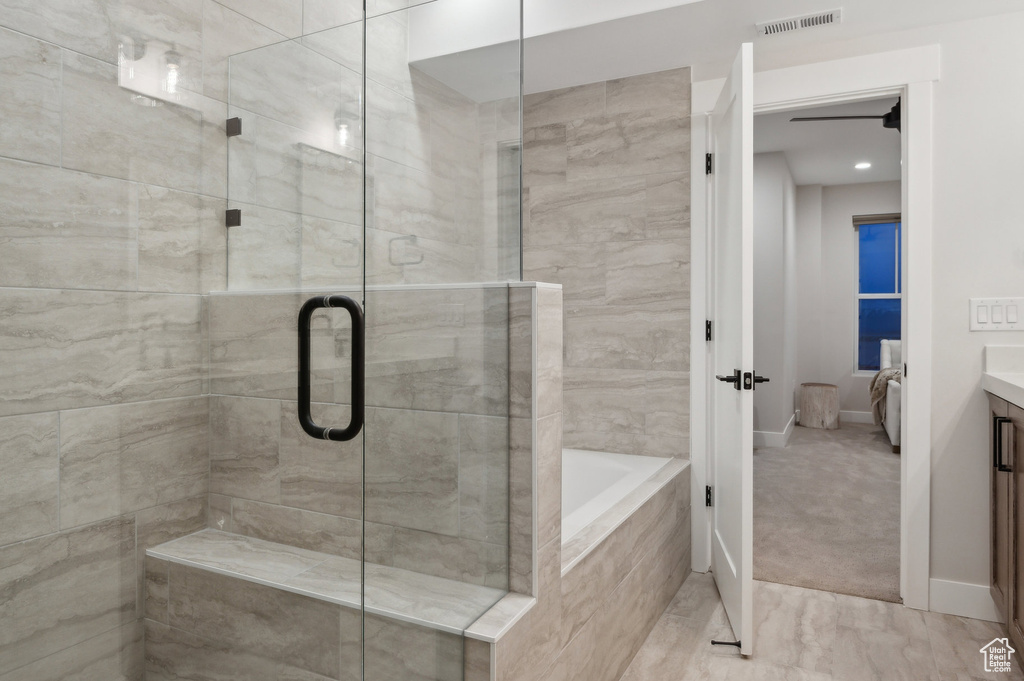 Bathroom with a shower stall, vanity, a bath, and baseboards