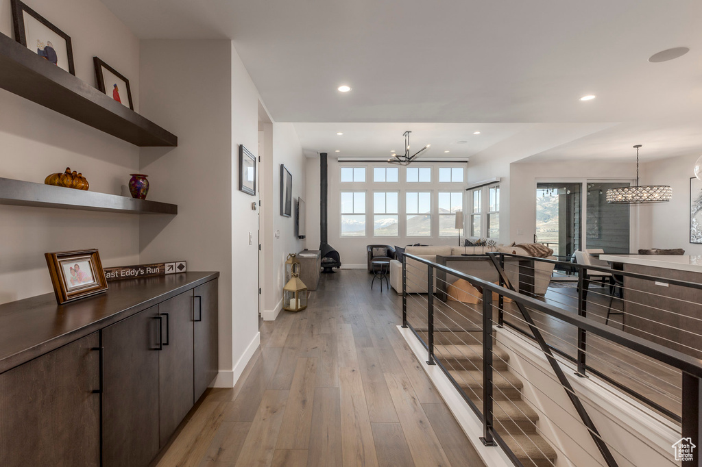 Corridor with a chandelier, baseboards, light wood-style flooring, and recessed lighting
