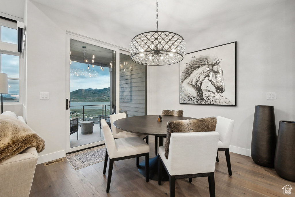 Dining space with plenty of natural light, a chandelier, wood finished floors, and baseboards