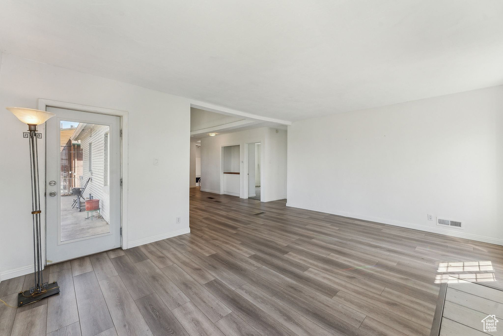 Unfurnished living room with baseboards, visible vents, and wood finished floors