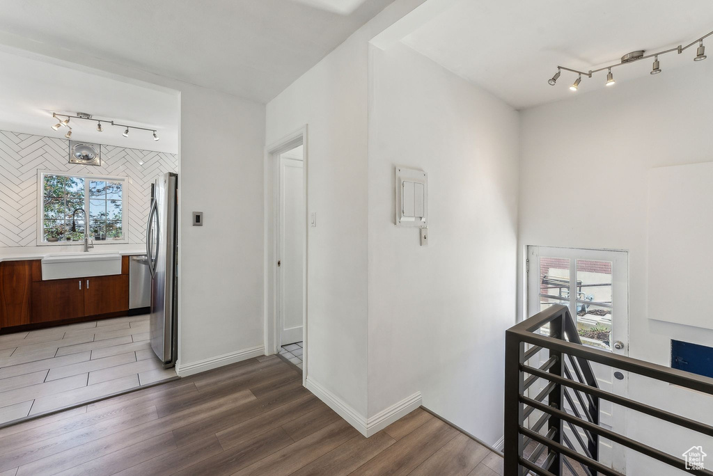 Corridor with track lighting, a sink, a healthy amount of sunlight, and light wood-type flooring