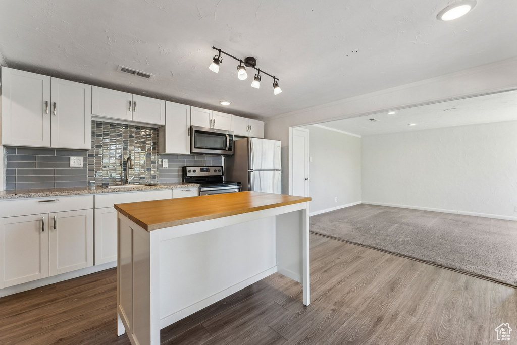 Kitchen featuring stainless steel appliances, white cabinetry, a sink, and tasteful backsplash