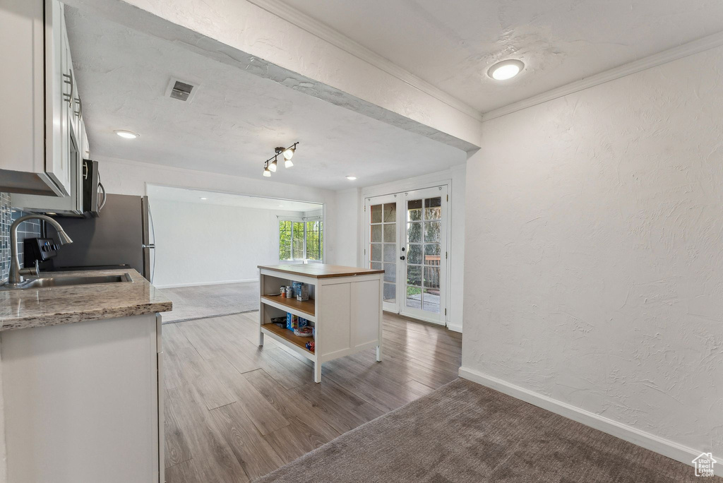 Kitchen featuring crown molding, open shelves, a sink, white cabinets, and a textured wall