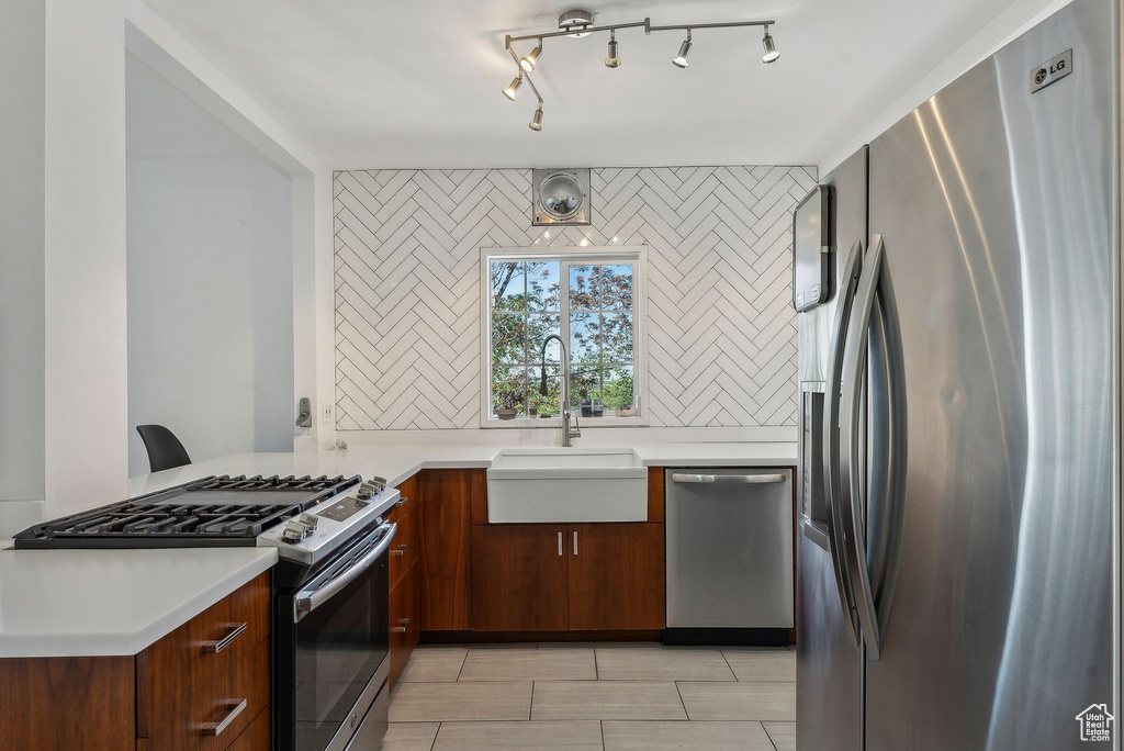 Kitchen featuring light countertops, stainless steel appliances, and a sink