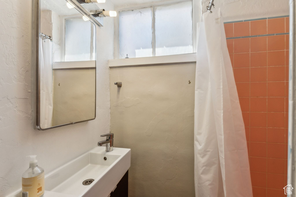 Bathroom with a shower with curtain, a textured wall, and a sink