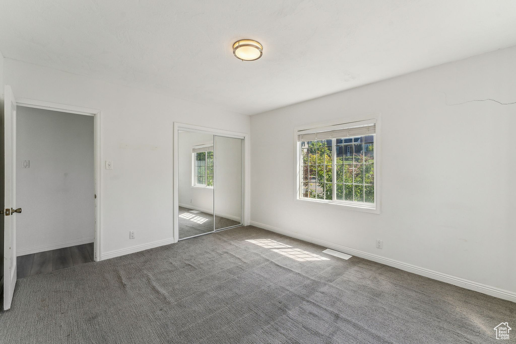 Unfurnished bedroom with carpet floors, baseboards, and a closet