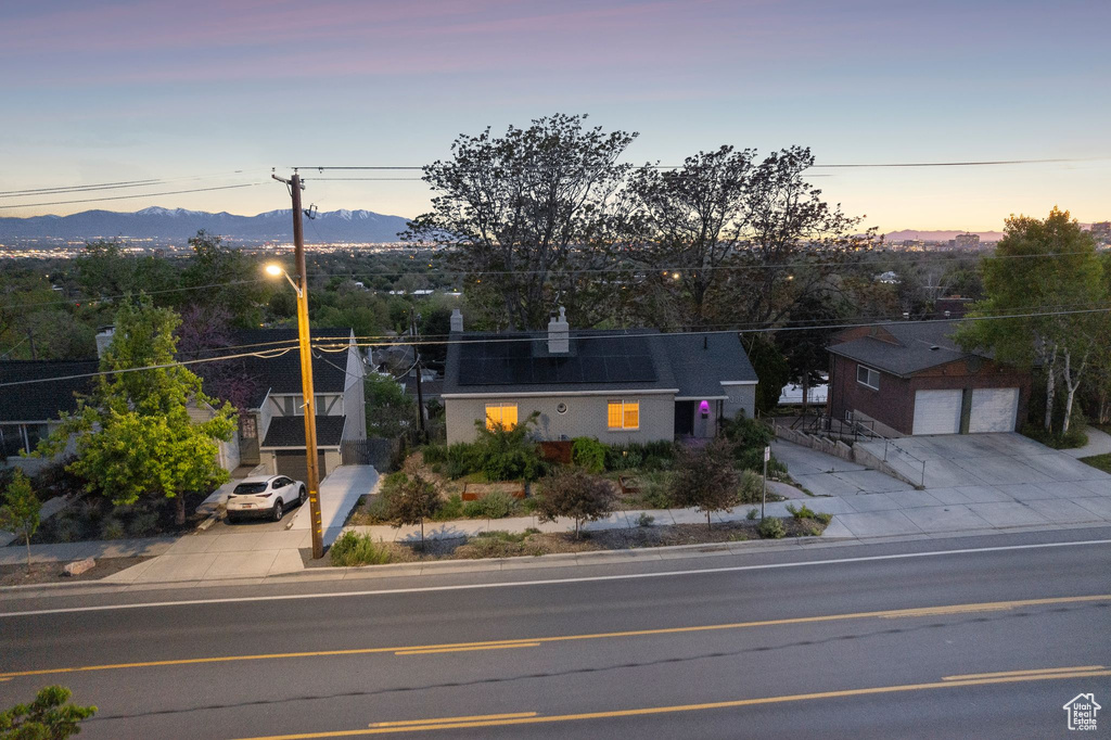 View of front of property with a mountain view, driveway, roof mounted solar panels, and a garage