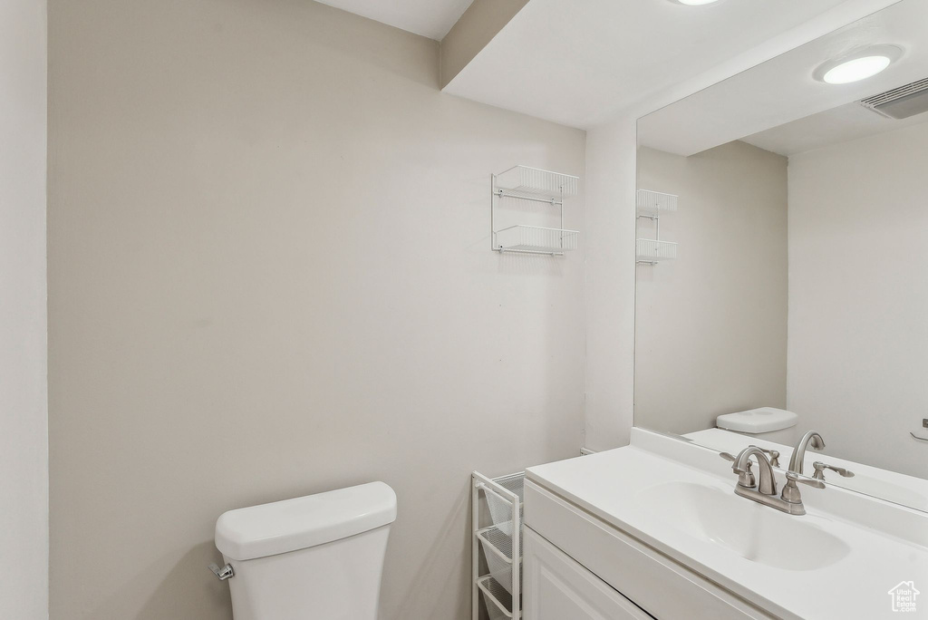 Half bath with visible vents, toilet, and vanity