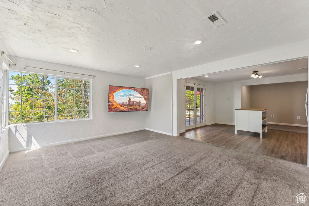 Unfurnished living room with carpet floors, baseboards, french doors, and visible vents