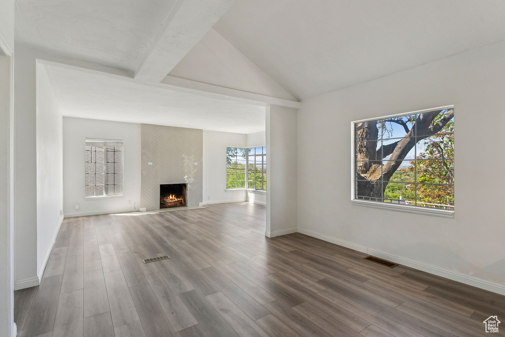 Unfurnished living room with visible vents, baseboards, wood finished floors, and a fireplace