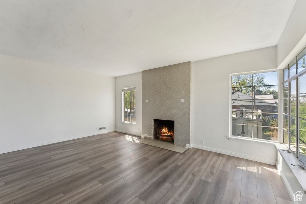 Unfurnished living room with baseboards, a fireplace, wood finished floors, and visible vents