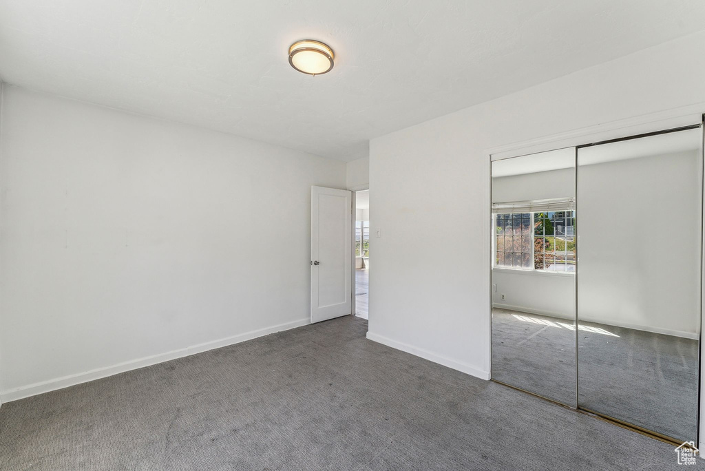 Unfurnished bedroom featuring a closet, carpet, baseboards, and multiple windows