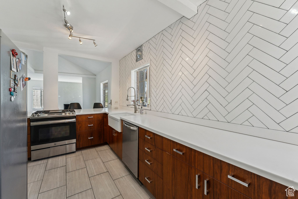 Kitchen with light countertops, a sink, modern cabinets, and stainless steel appliances