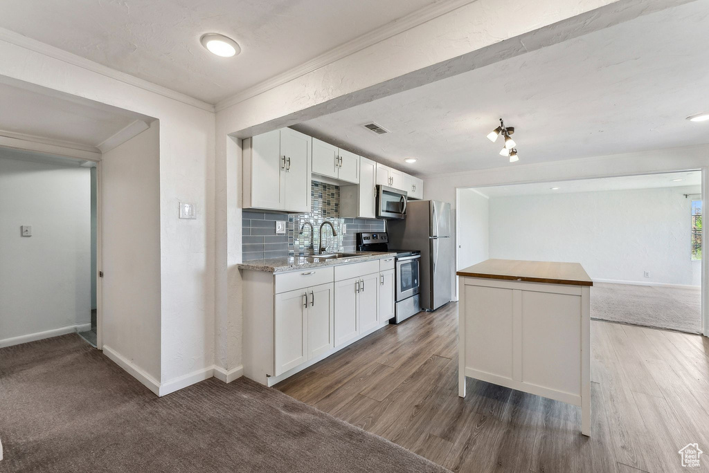 Kitchen with visible vents, ornamental molding, white cabinetry, a sink, and stainless steel appliances