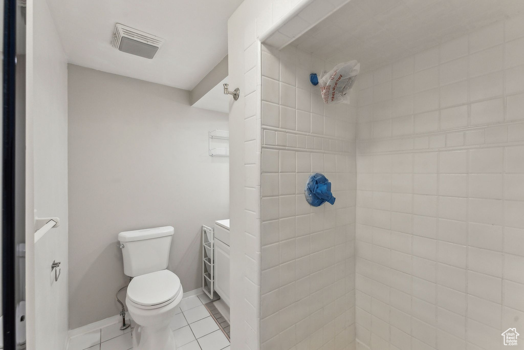 Bathroom with tile patterned floors, toilet, tiled shower, and visible vents