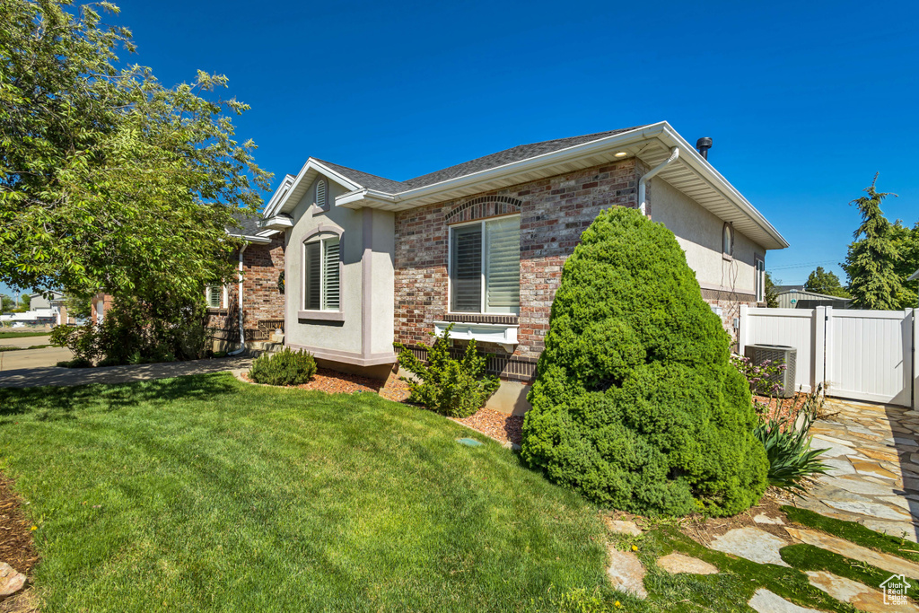 View of side of property featuring brick siding, central air condition unit, and stucco siding