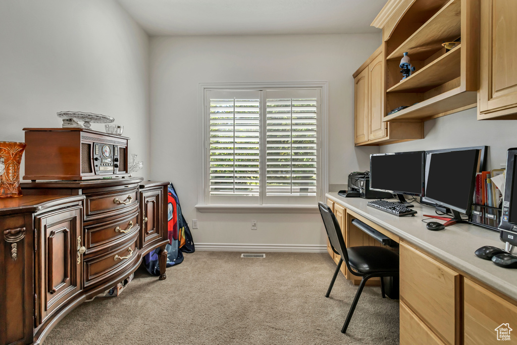Office space featuring carpet floors, built in desk, and baseboards