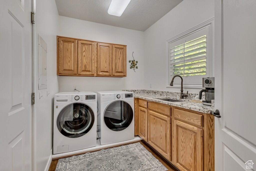 Clothes washing area featuring cabinet space, independent washer and dryer, a textured ceiling, and wood finished floors
