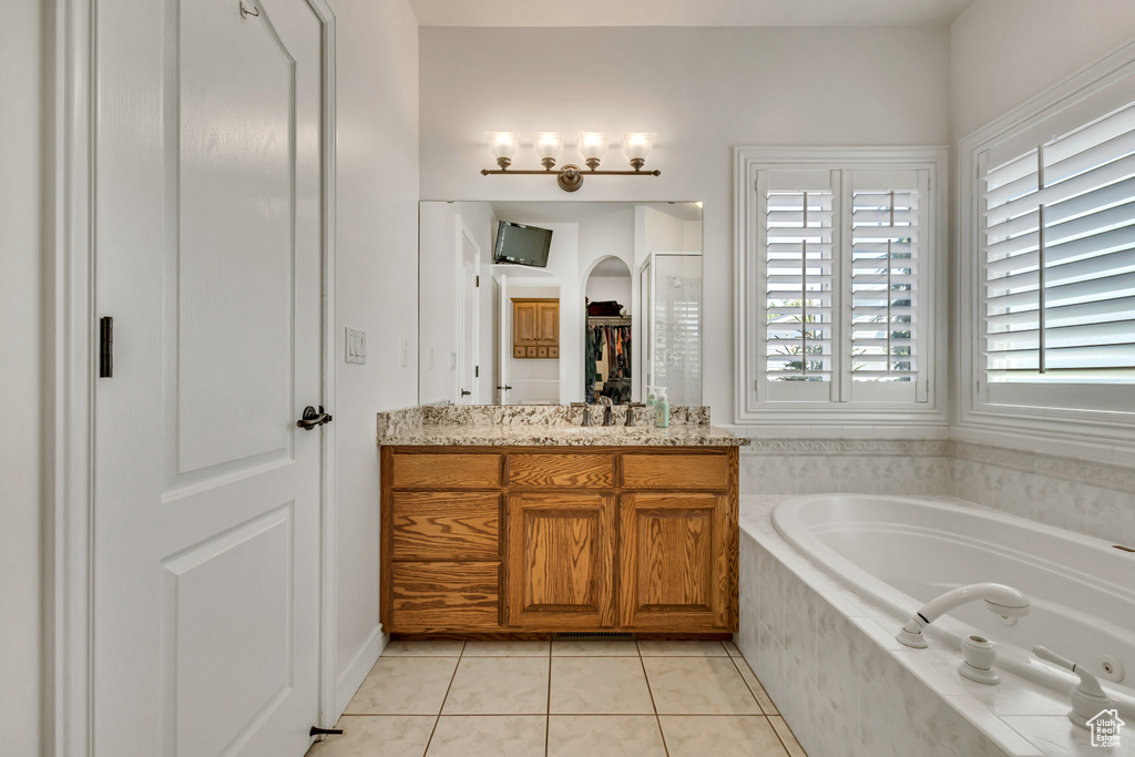 Full bathroom featuring a bath, tile patterned floors, vanity, and a walk in closet