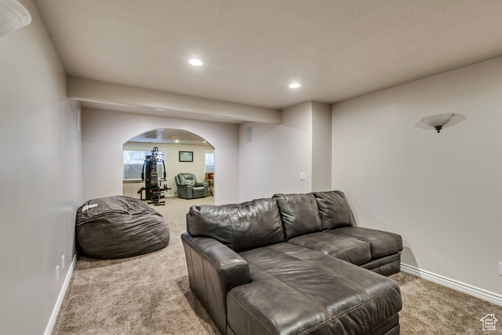 Carpeted living room featuring arched walkways, recessed lighting, and baseboards