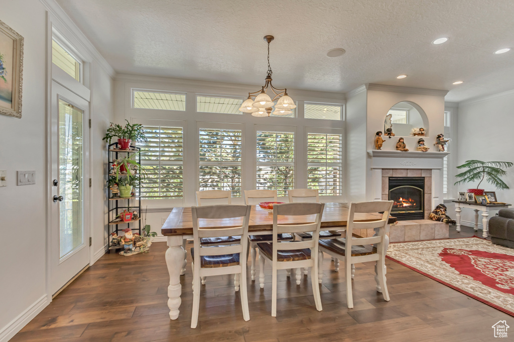 Dining room featuring ornamental molding, a fireplace, wood finished floors, a chandelier, and recessed lighting
