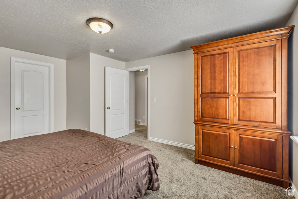 Bedroom featuring light colored carpet, a textured ceiling, and baseboards