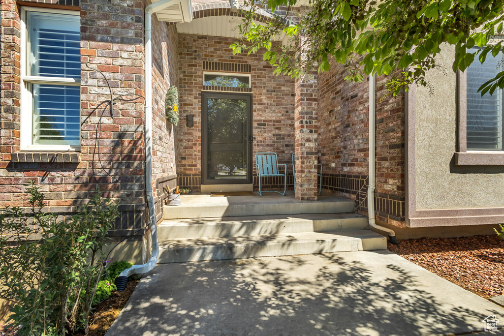 Entrance to property featuring brick siding and covered porch