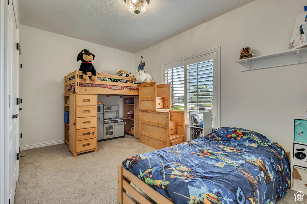 Bedroom featuring light colored carpet, baseboards, and a textured ceiling