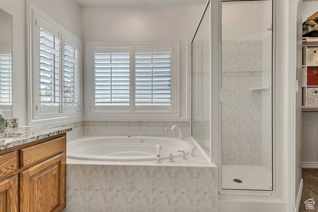 Bathroom featuring a shower stall, a bath, and vanity
