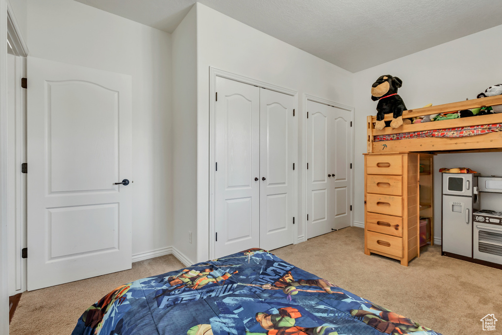 Bedroom featuring light colored carpet and multiple closets